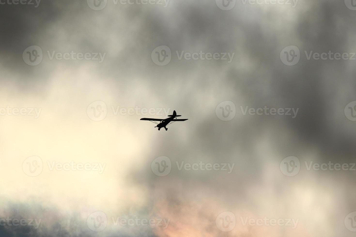 petit avion en volant dans le ciel contre foncé des nuages photo