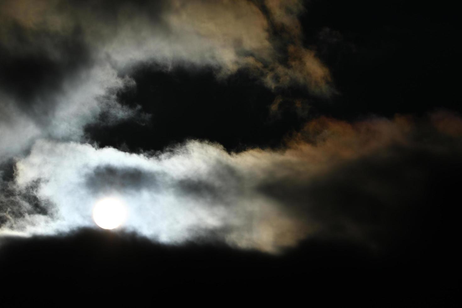 Soleil disque derrière rétro-éclairé des nuages photo