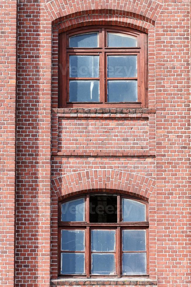 deux fenêtres en verre cintrées dans un mur de briques rouges photo