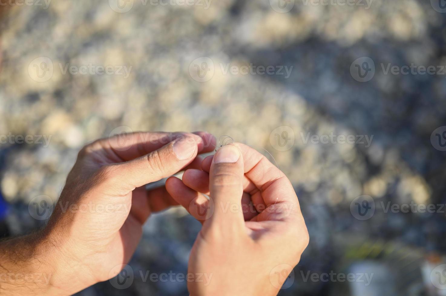 Les mains de l'homme attachant une ligne de pêche sur un hameçon photo