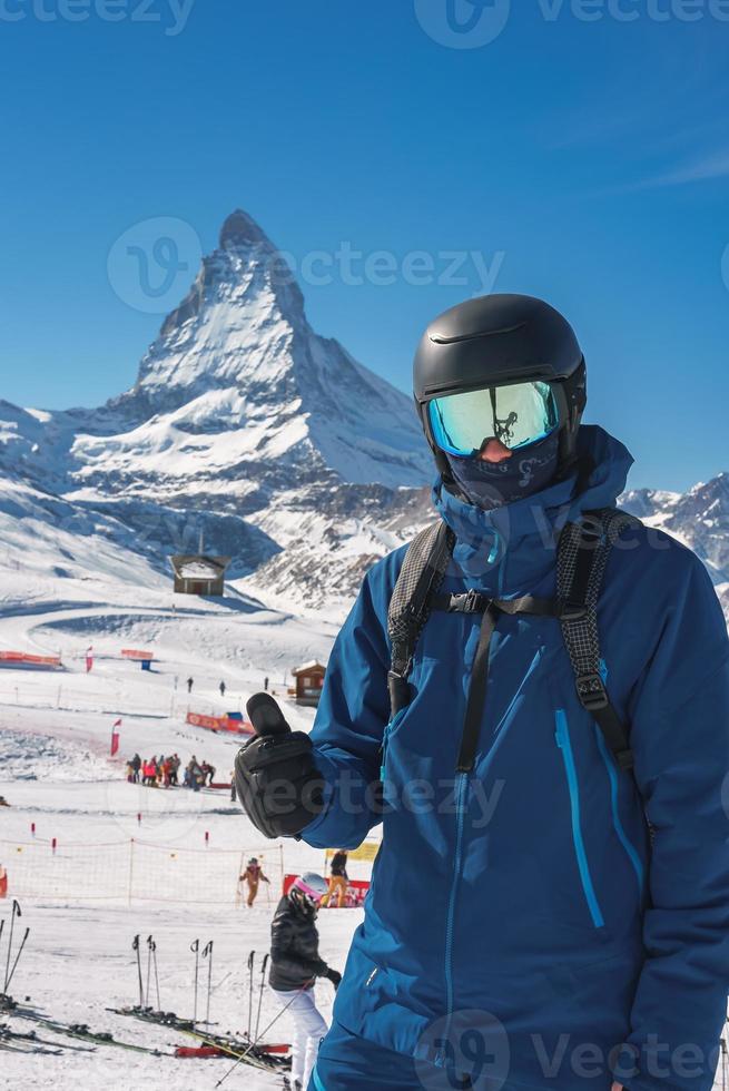 Jeune skieur profiter Zermatt ski station balnéaire. magnifique ensoleillé journée avec une skieur en haut dans le montagnes. des sports modèle. photo