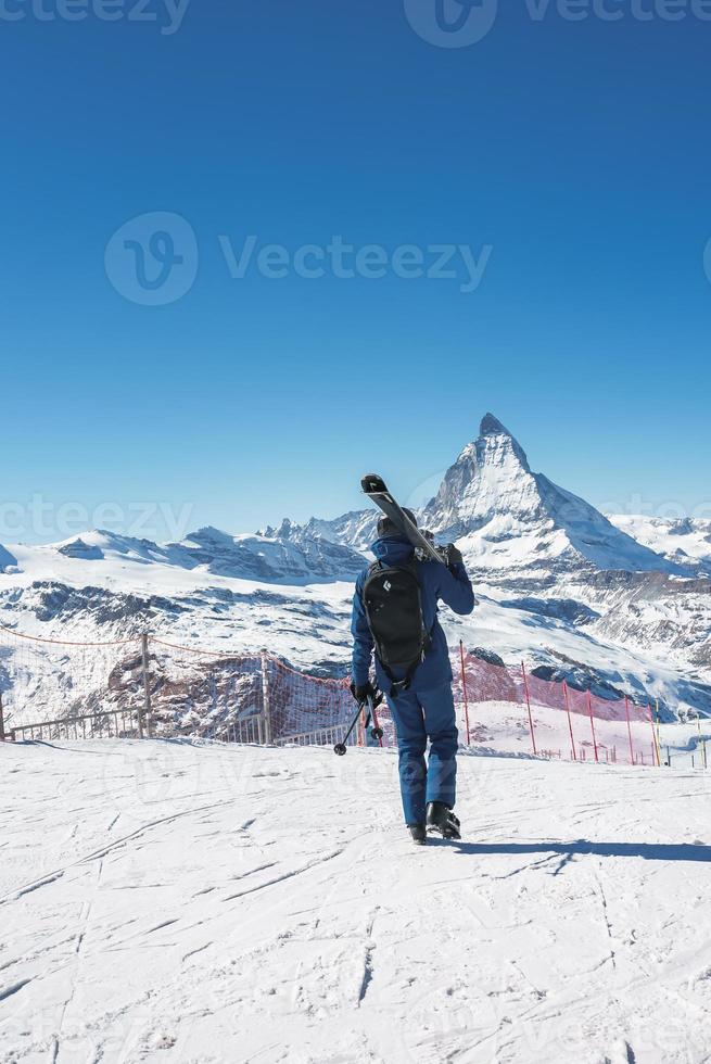 Jeune skieur profiter Zermatt ski station balnéaire. magnifique ensoleillé journée avec une skieur en haut dans le montagnes. des sports modèle. photo