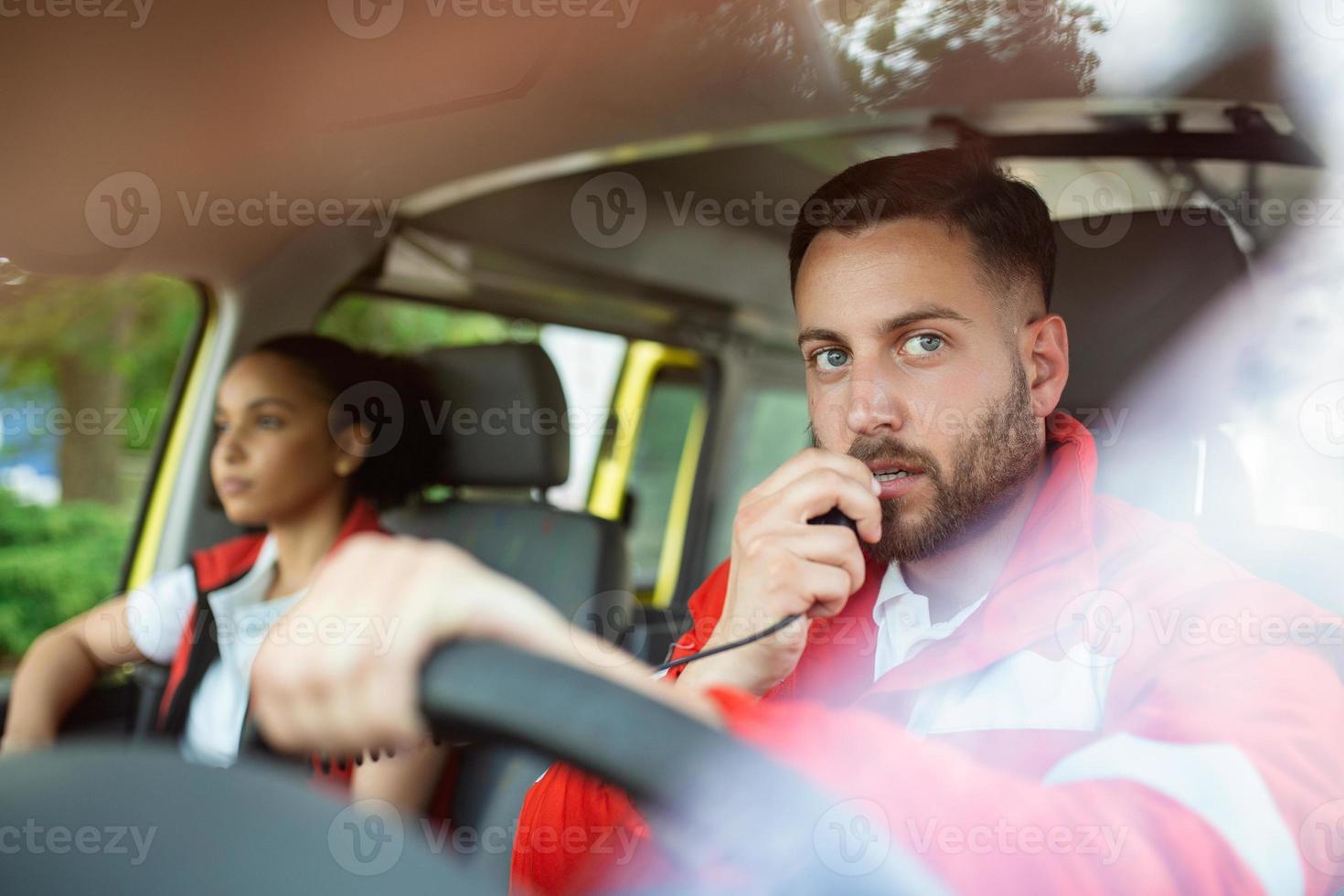 urgent situation. deux Jeune ambulanciers dans ambulance. homme, caucasien paramédical conduite et parlant plus de le radio photo