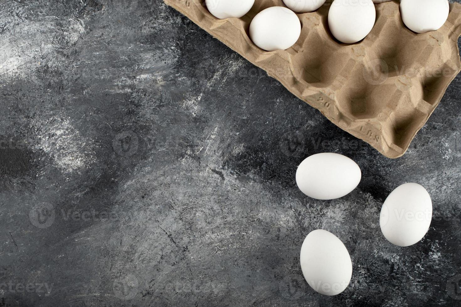 Œufs de poule crus dans une boîte à œufs sur un fond de marbre photo