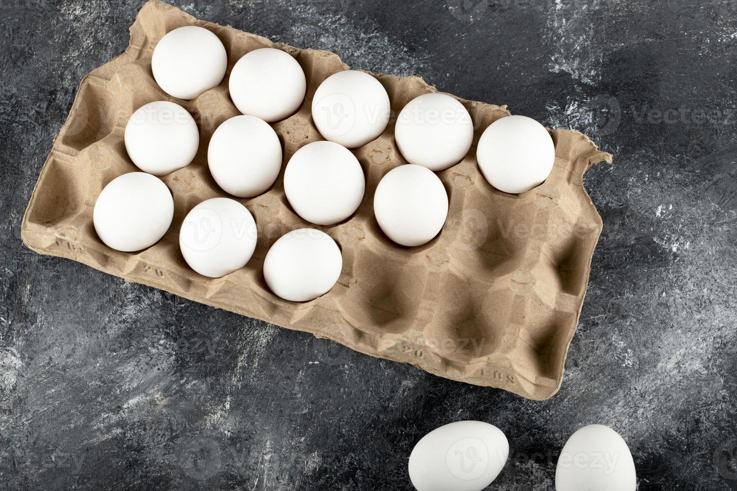 Œufs de poule crus dans une boîte à œufs sur un fond de marbre photo