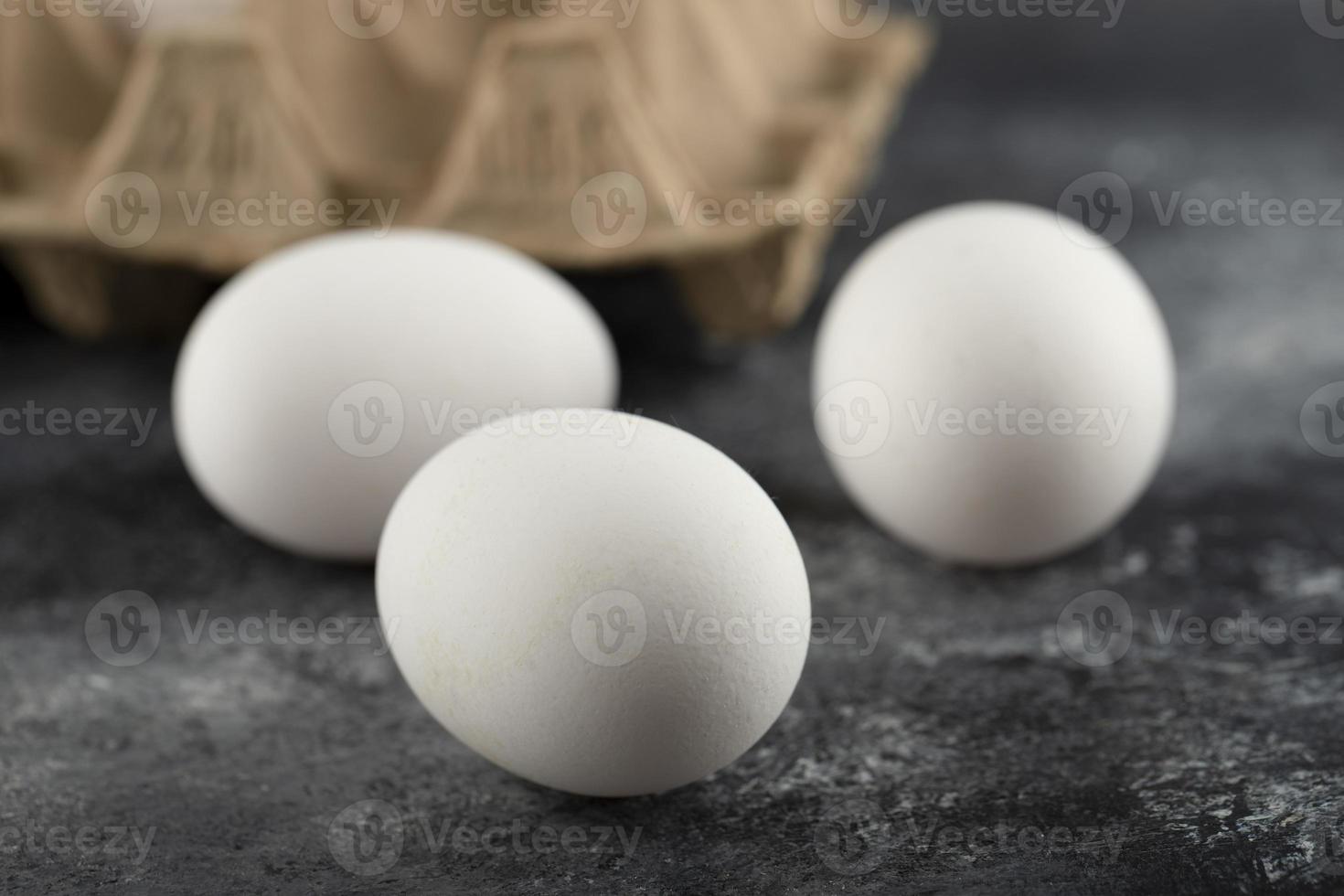 Trois œufs frais de poulet cru sur un fond de marbre photo