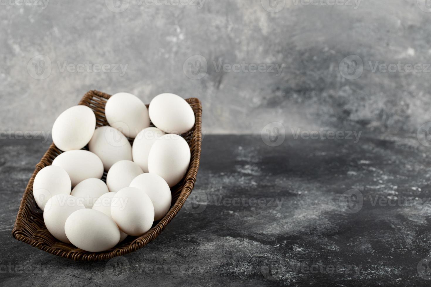 un osier en bois plein d'oeufs de poule crus blancs photo