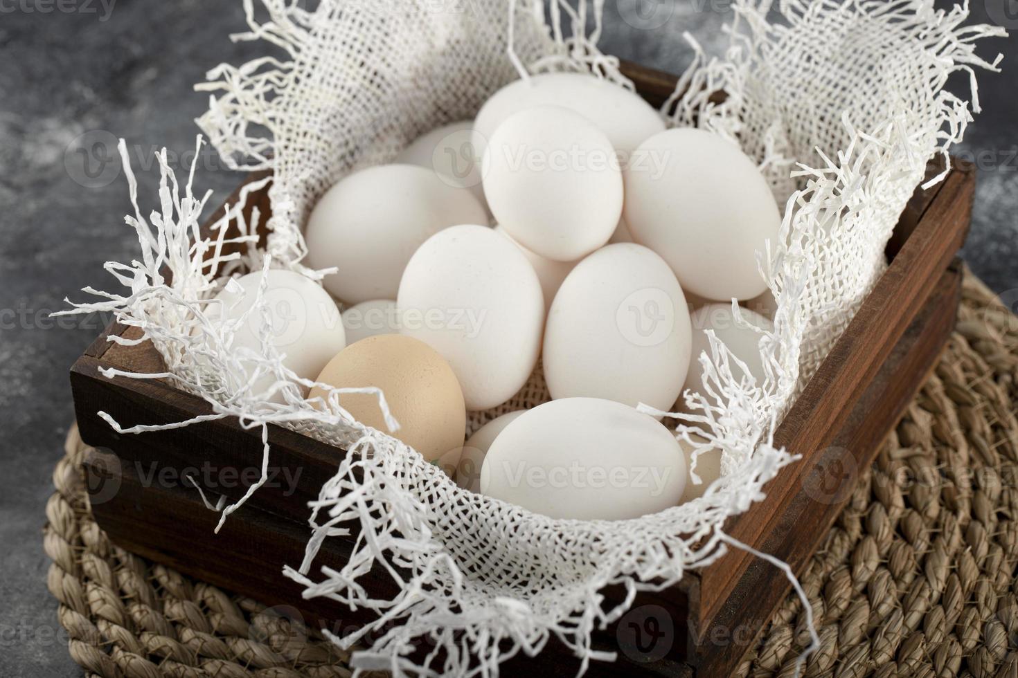 un panier en bois plein d'oeufs de poule crus blancs photo