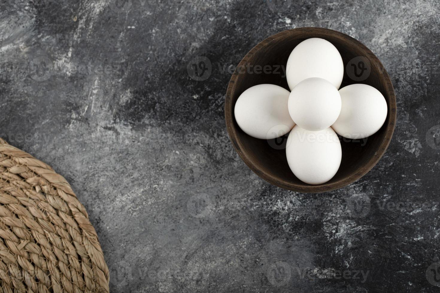 bol en bois plein d'oeufs de poule crus blancs photo