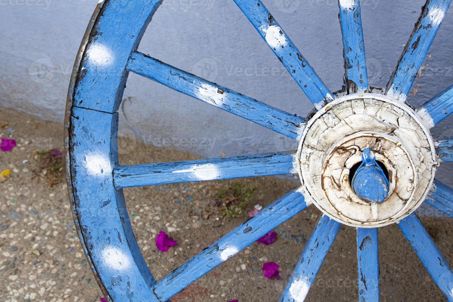 vieux en bois bleu roue, proche en haut vue de le roue. le vieux en bois roue sur le Contexte de le bleu mur de le maison photo