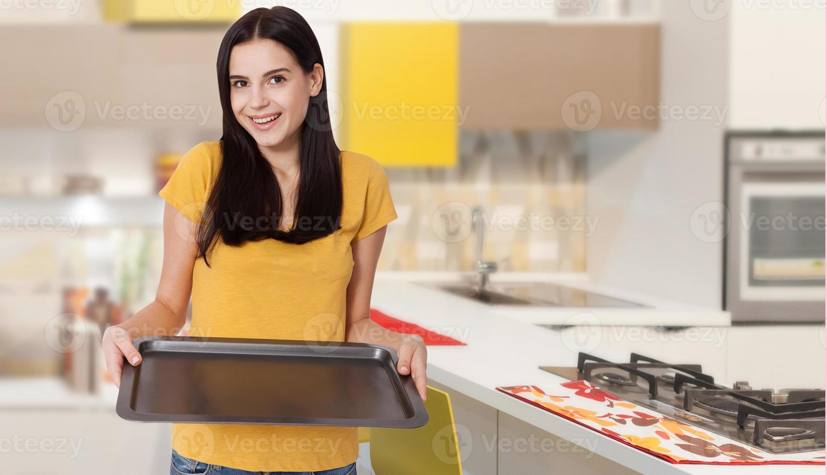 cuisine femme donne un plateau vide pour vos produits publicitaires à la maison dans la cuisine. maquette à utiliser photo