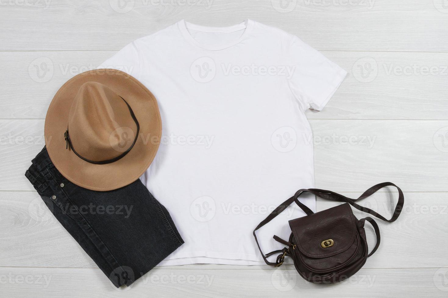 blanc T-shirt maquette. modèle Vide chemise Haut vue sur blanc en bois Contexte. printemps été tenue sur bois sol. femme mode vêtements. l'automne Regardez de aujourd'hui. femelle jeans, chapeau, sac accessoires photo