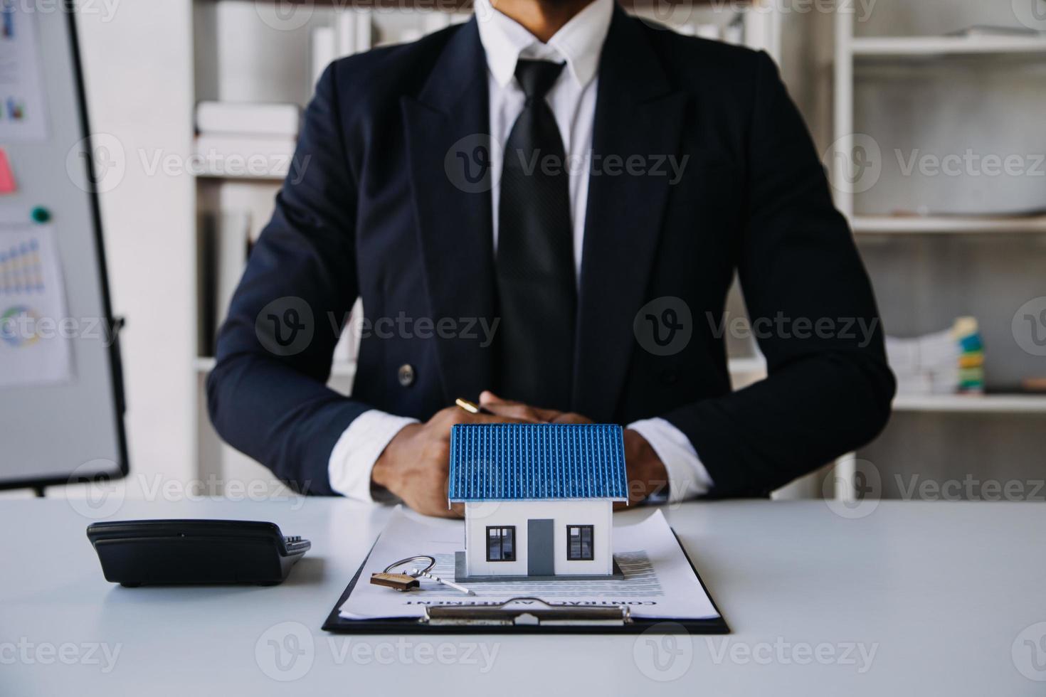 modèle de maison avec agent immobilier et client discutant d'un contrat d'achat de maison, d'assurance ou de prêt immobilier. photo