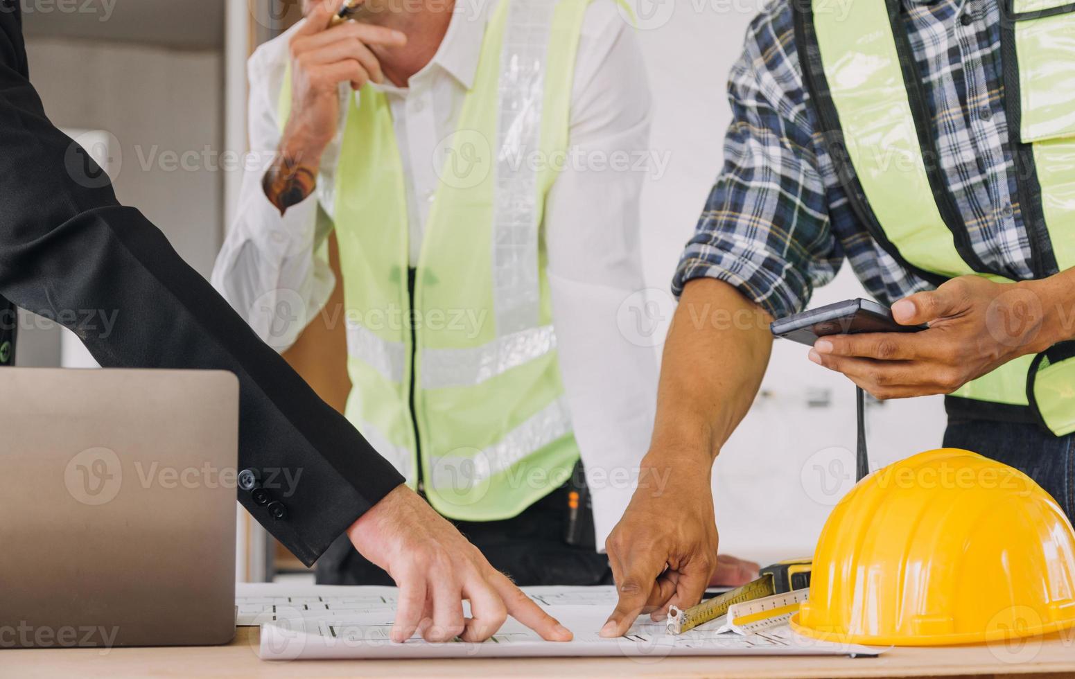 diverse équipe de spécialistes utilisation tablette ordinateur sur construction placer. réel biens bâtiment projet avec civil ingénieur, architecte, affaires investisseur et général ouvrier discuter plan détails. photo