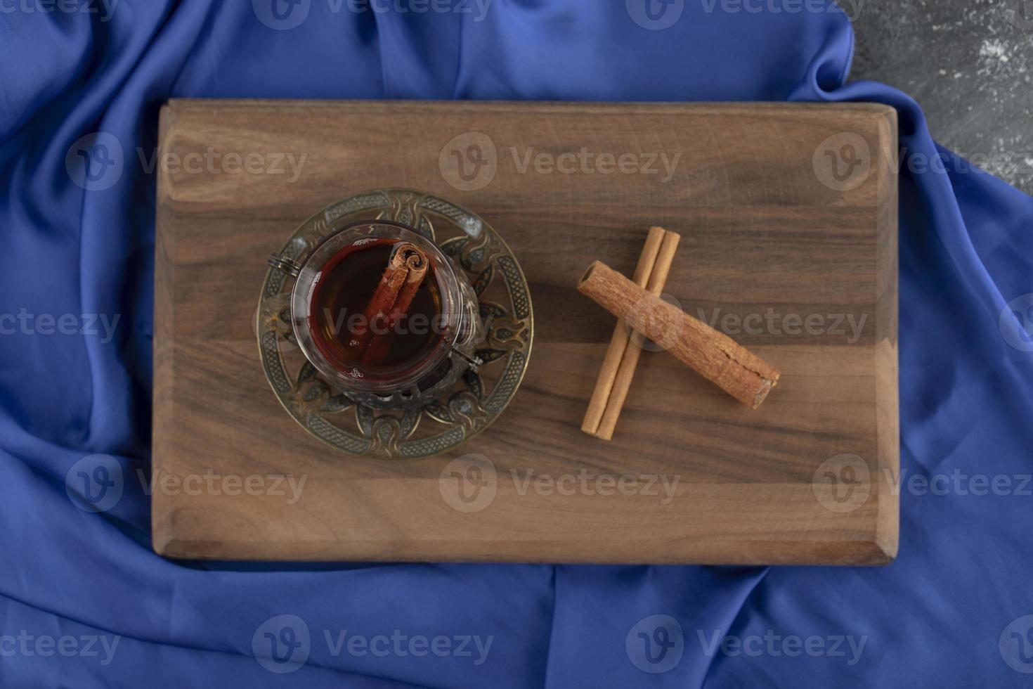 un thé en verre avec des bâtons de cannelle sur une planche à découper en bois photo