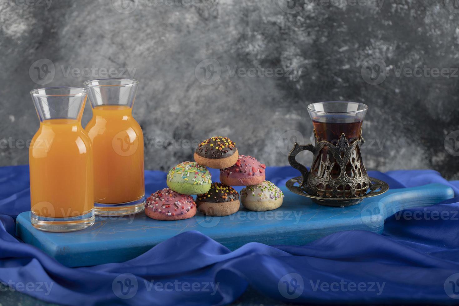 beignets sucrés colorés avec des pots en verre de jus et une tasse de thé photo