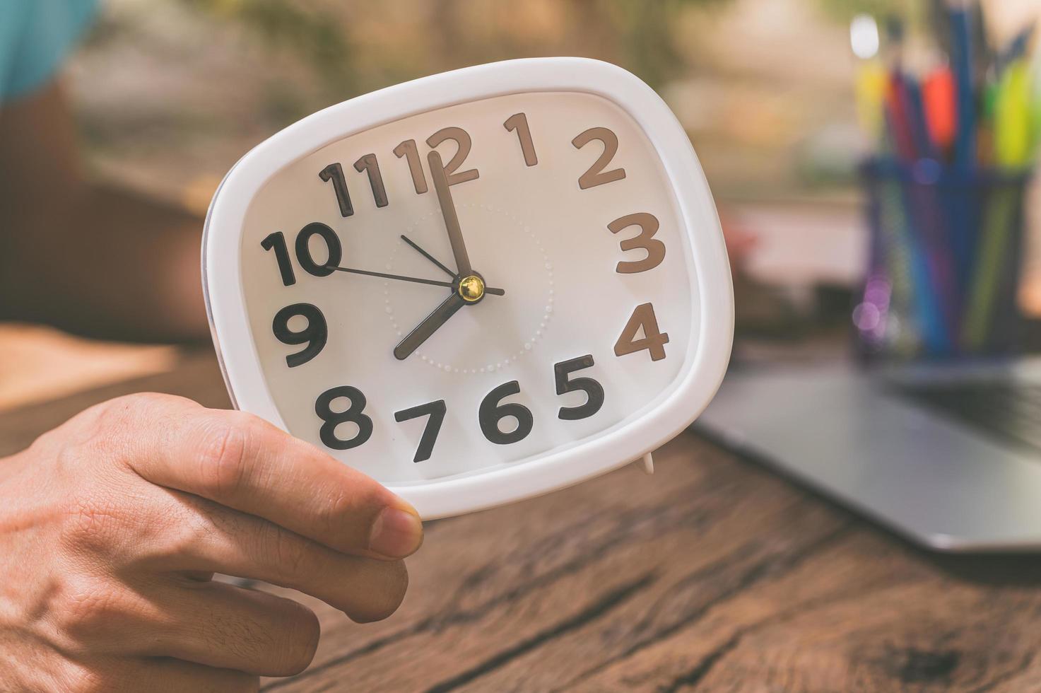 la main d'une personne tenant une horloge à un bureau photo