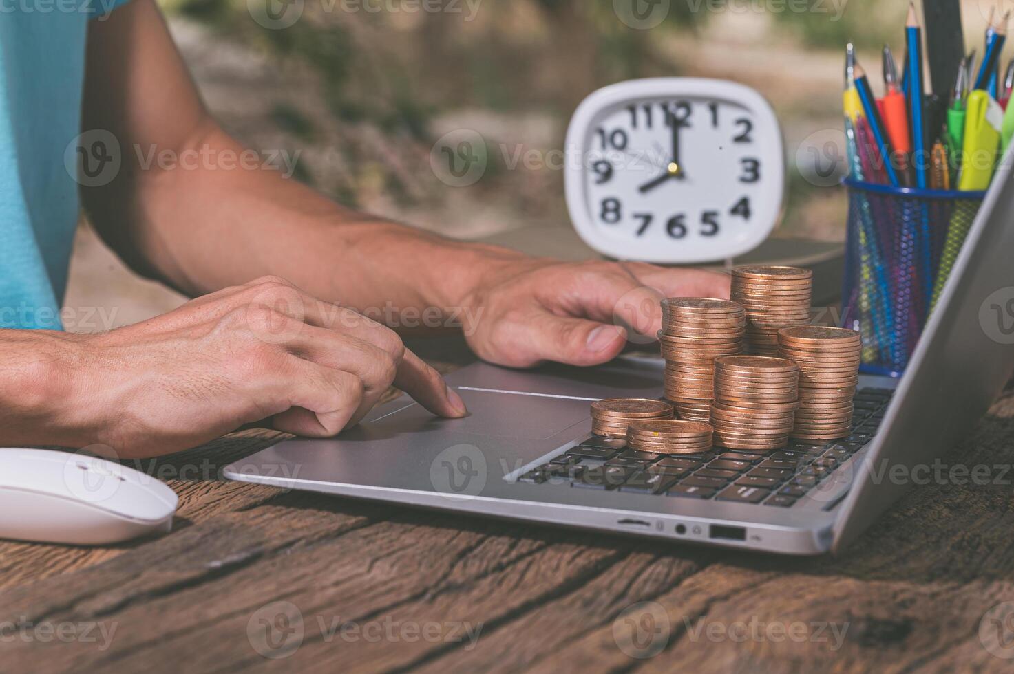 Une personne utilisant un ordinateur avec une pile de pièces de monnaie, gagner de l'argent en ligne concept photo