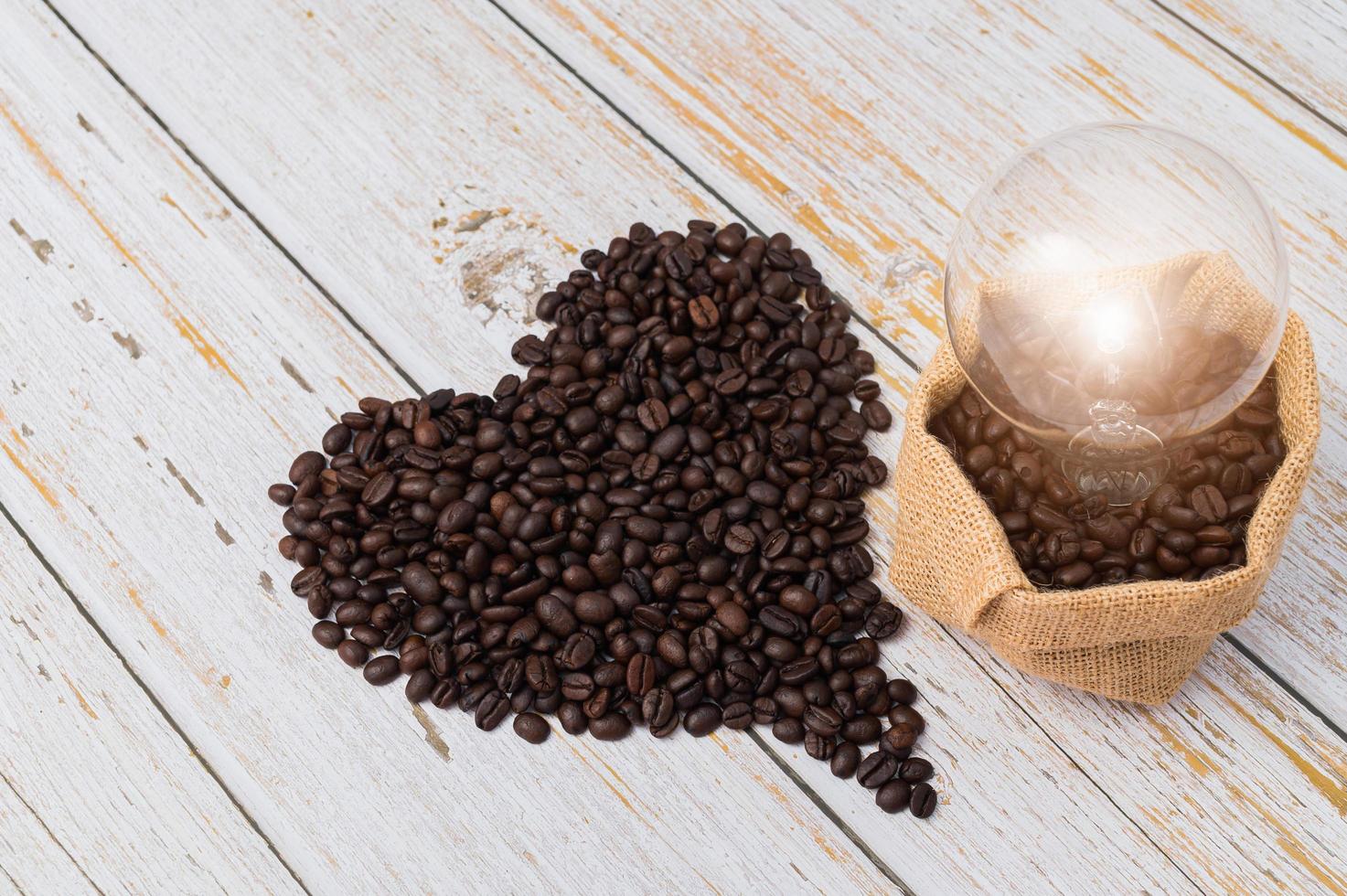 grains de café en forme de coeur et une ampoule sur une table en bois photo