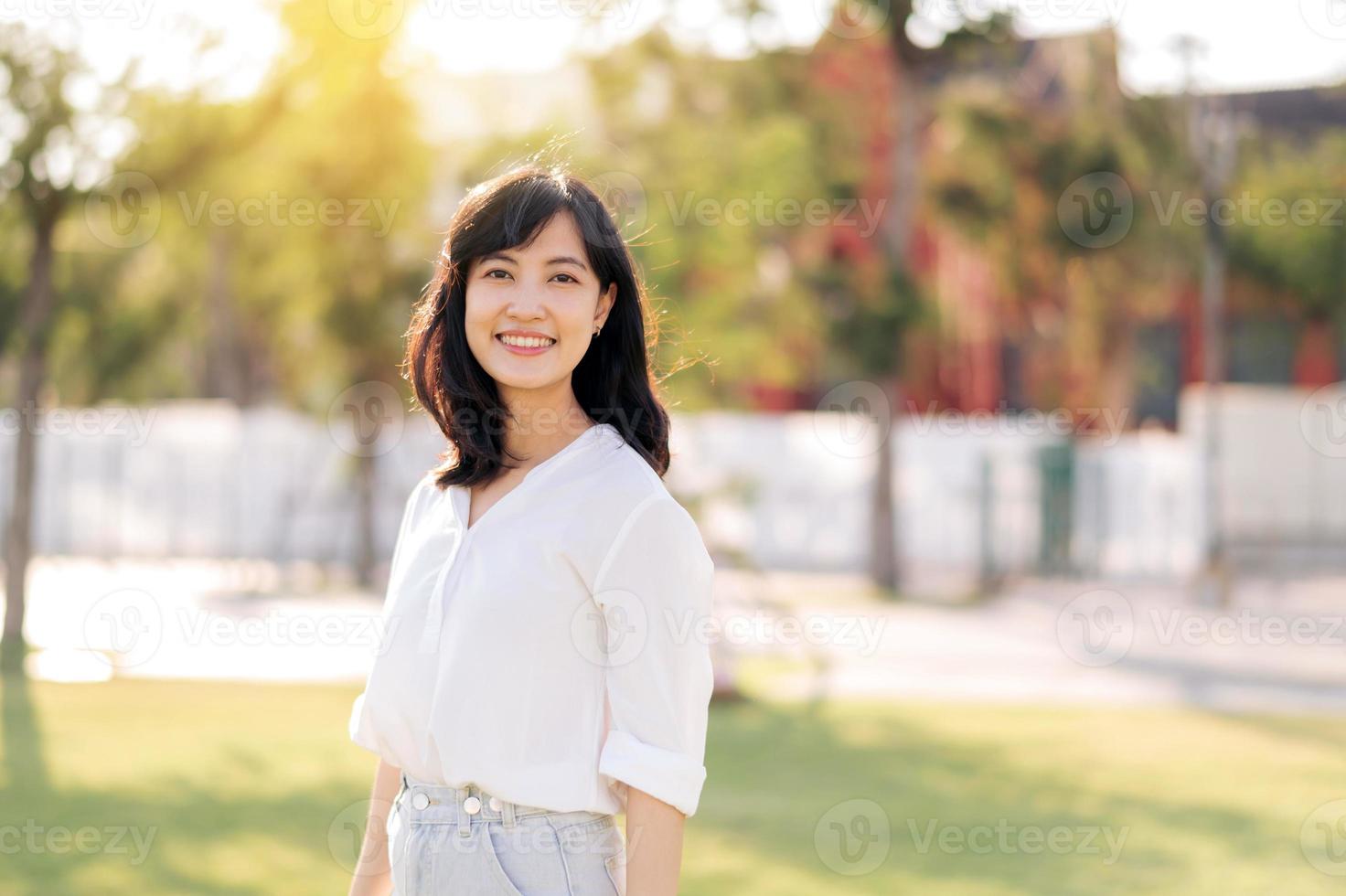 portrait Jeune magnifique asiatique femme avec content sourire autour Extérieur parc dans ensoleillé été journée photo