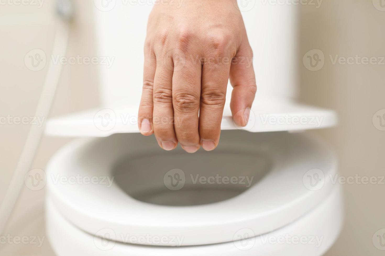 proche en haut main de une femme fermeture le couvercle de une toilette siège. hygiène et santé se soucier concept. photo