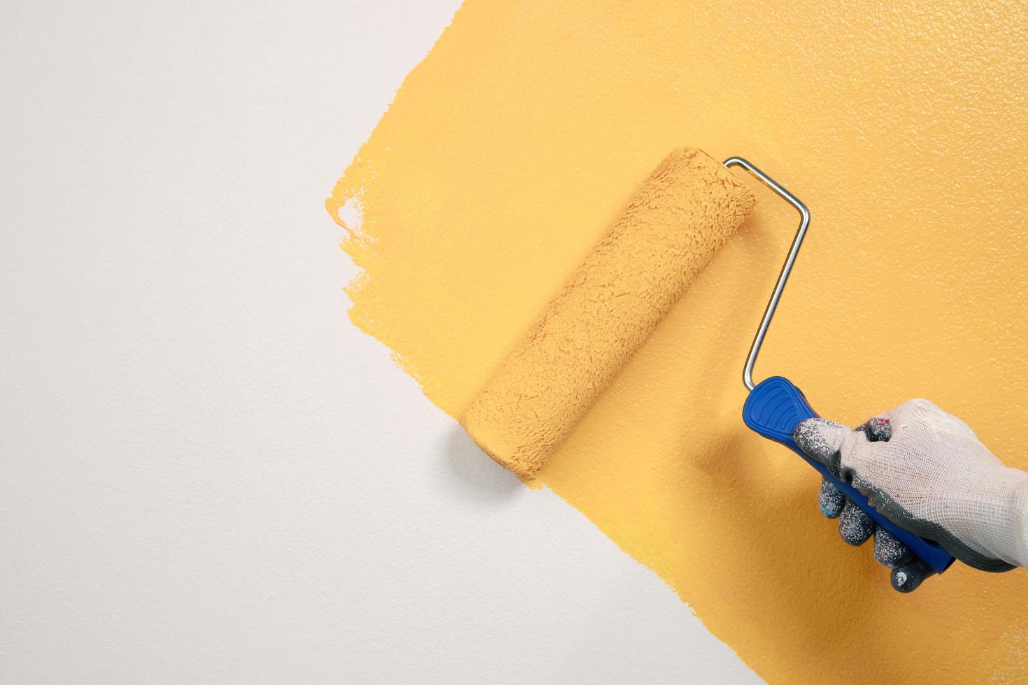 peinture au pinceau au rouleau, ouvrier peignant sur un appartement de peinture murale en surface, rénovant avec de la peinture de couleur jaune. laissez un espace de copie vide blanc pour écrire un texte descriptif à côté. photo