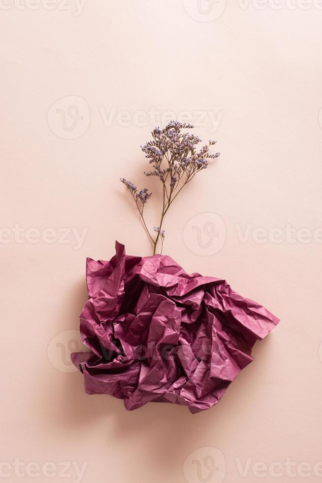 le concept de la dépression et stagnation. sec fleur de une liasse de papier sur une rose Contexte. verticale vue photo