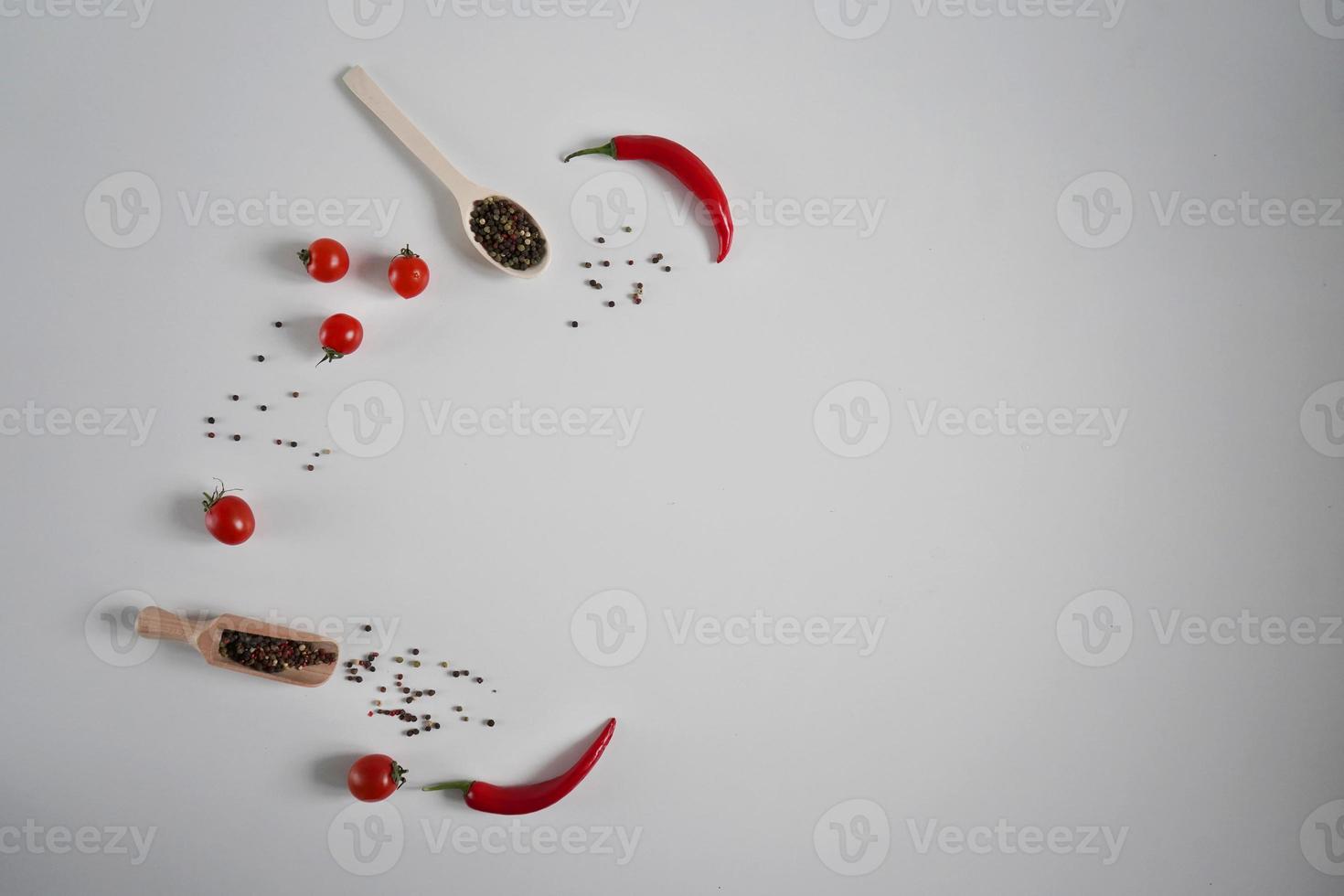 Cerise tomates, rouge chaud le Chili poivre, parfumé noir poivre pois sur une blanc Contexte. Contexte avec épices. plat poser, Haut vue et copie espace photo
