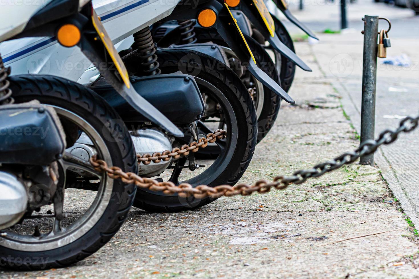 les roues arrière de la chaîne du scooter de livraison de pizza sont verrouillées avec une chaîne antivol photo