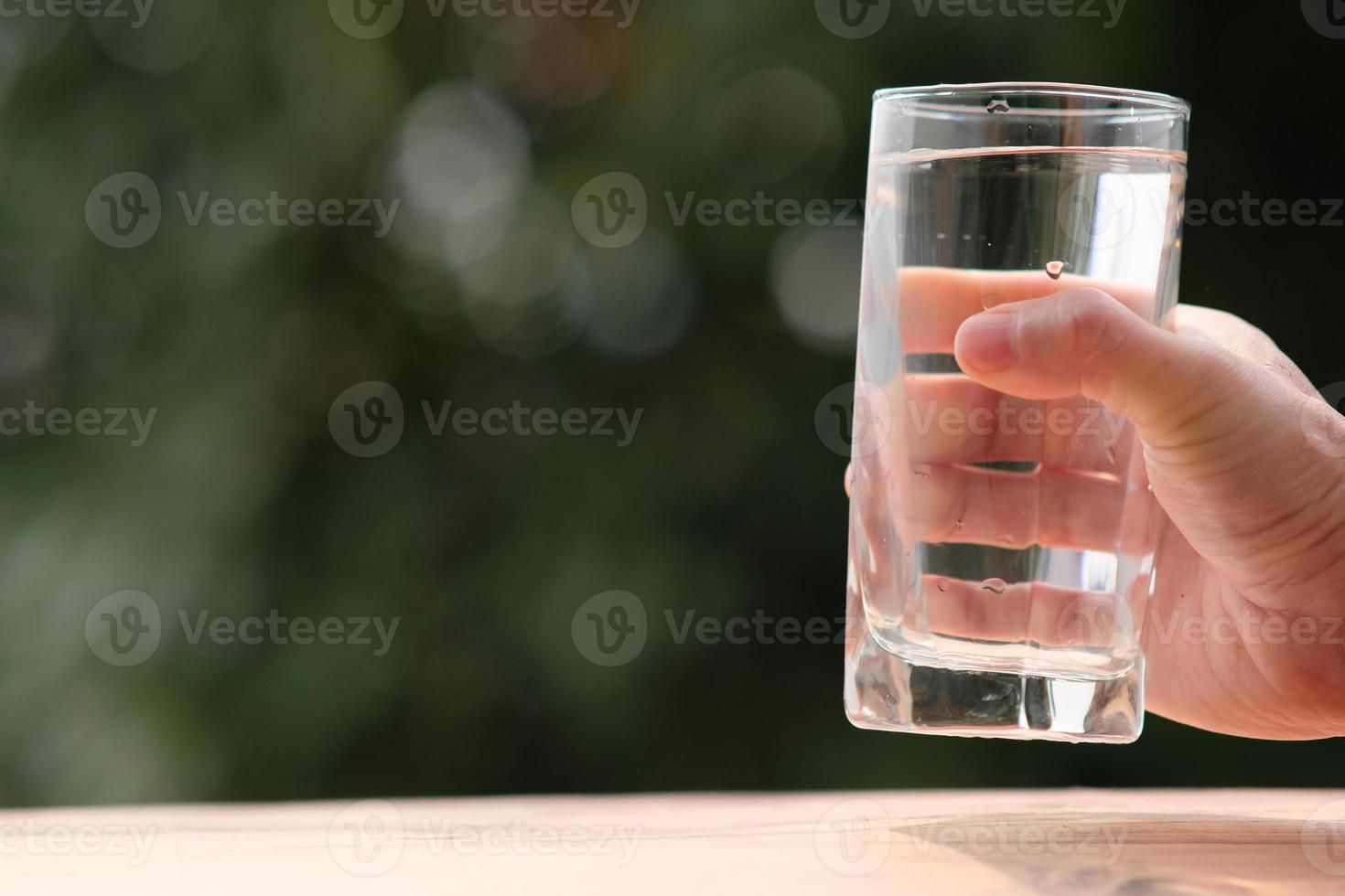 Eau potable minérale sur table en bois et eau en verre photo
