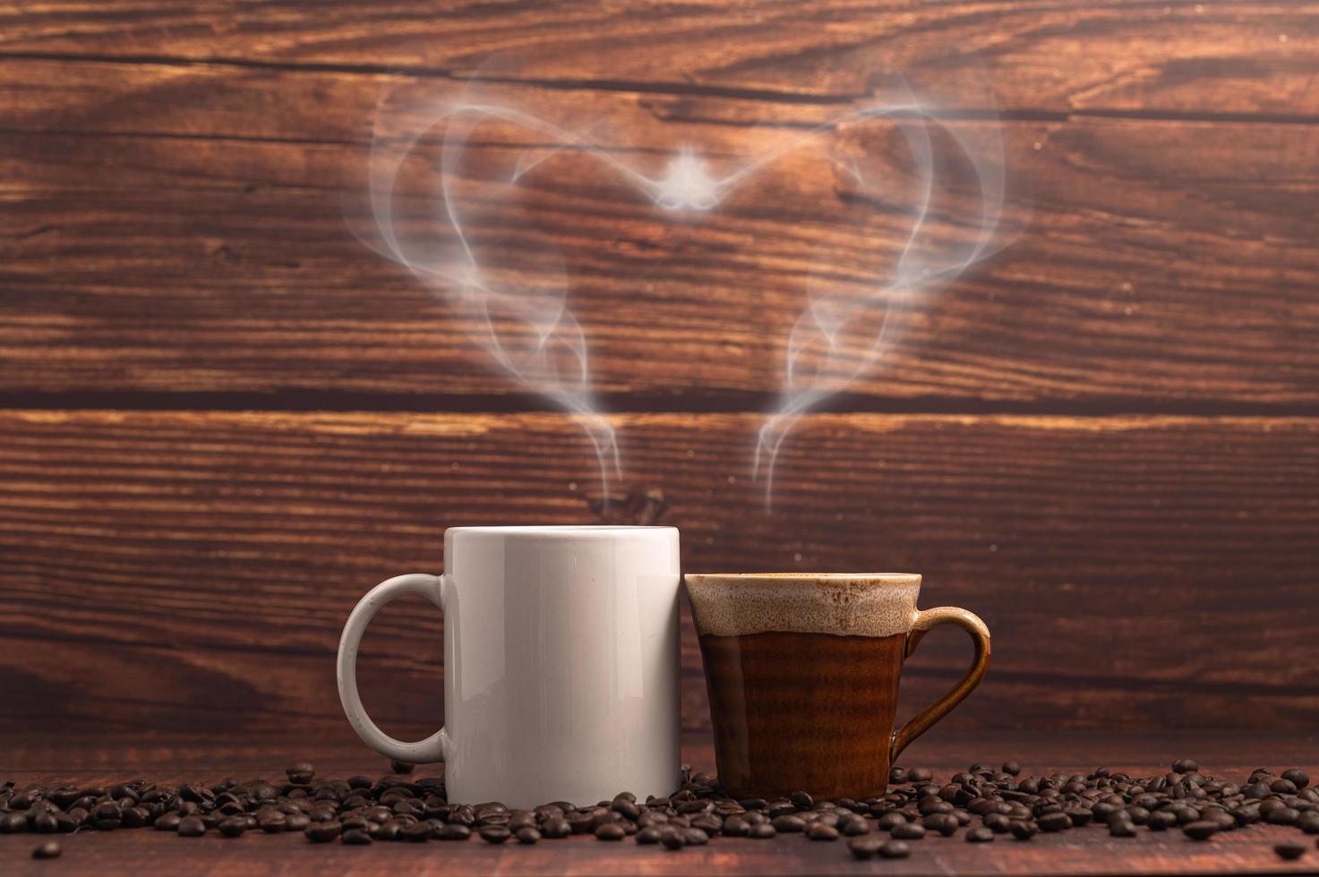 Tasses à café faisant de la vapeur en forme de coeur sur une table en bois photo
