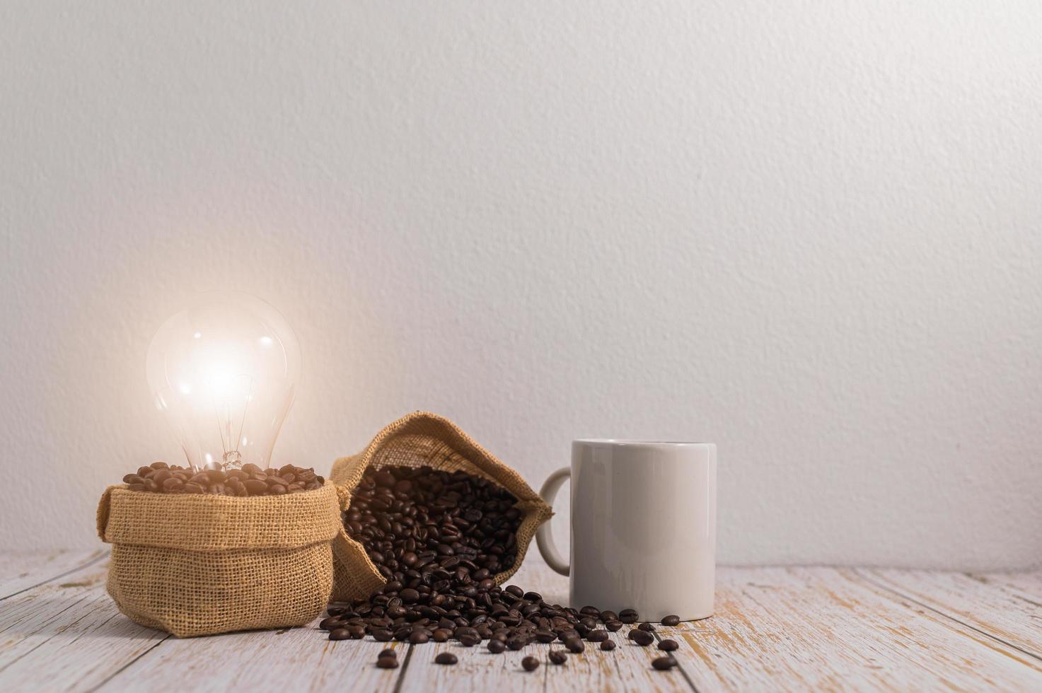 Une tasse de café avec des sacs de grains de café et une ampoule émettant de l'énergie sur une table en bois photo