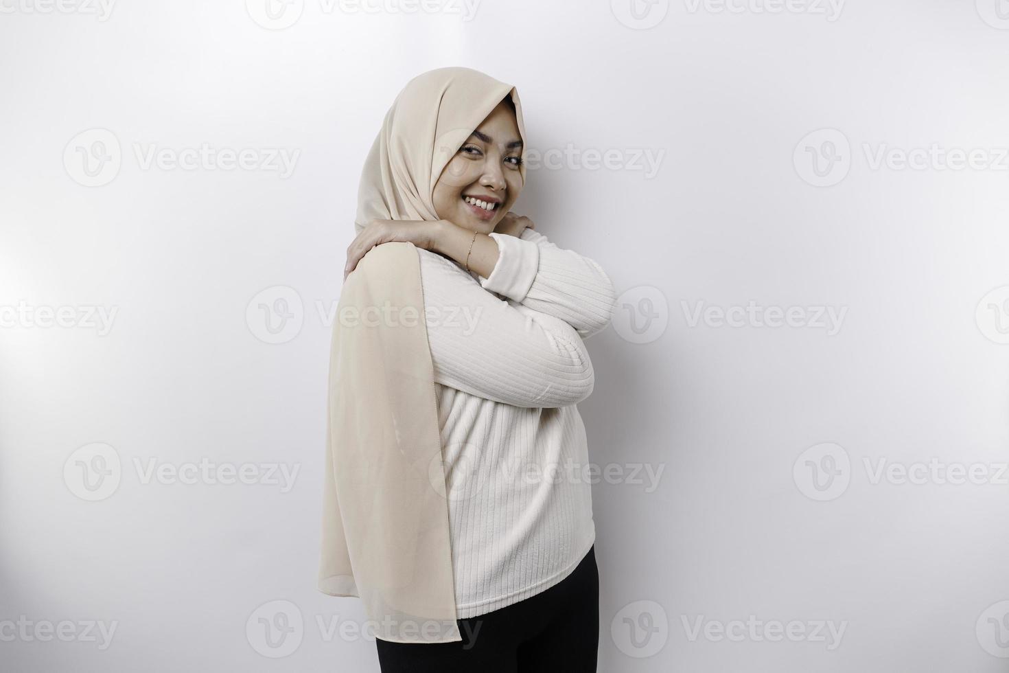 Jeune magnifique asiatique musulman femme portant une foulard plus de blanc Contexte étreindre se content et positif, souriant confiant. l'amour de soi et soins auto-administrés photo