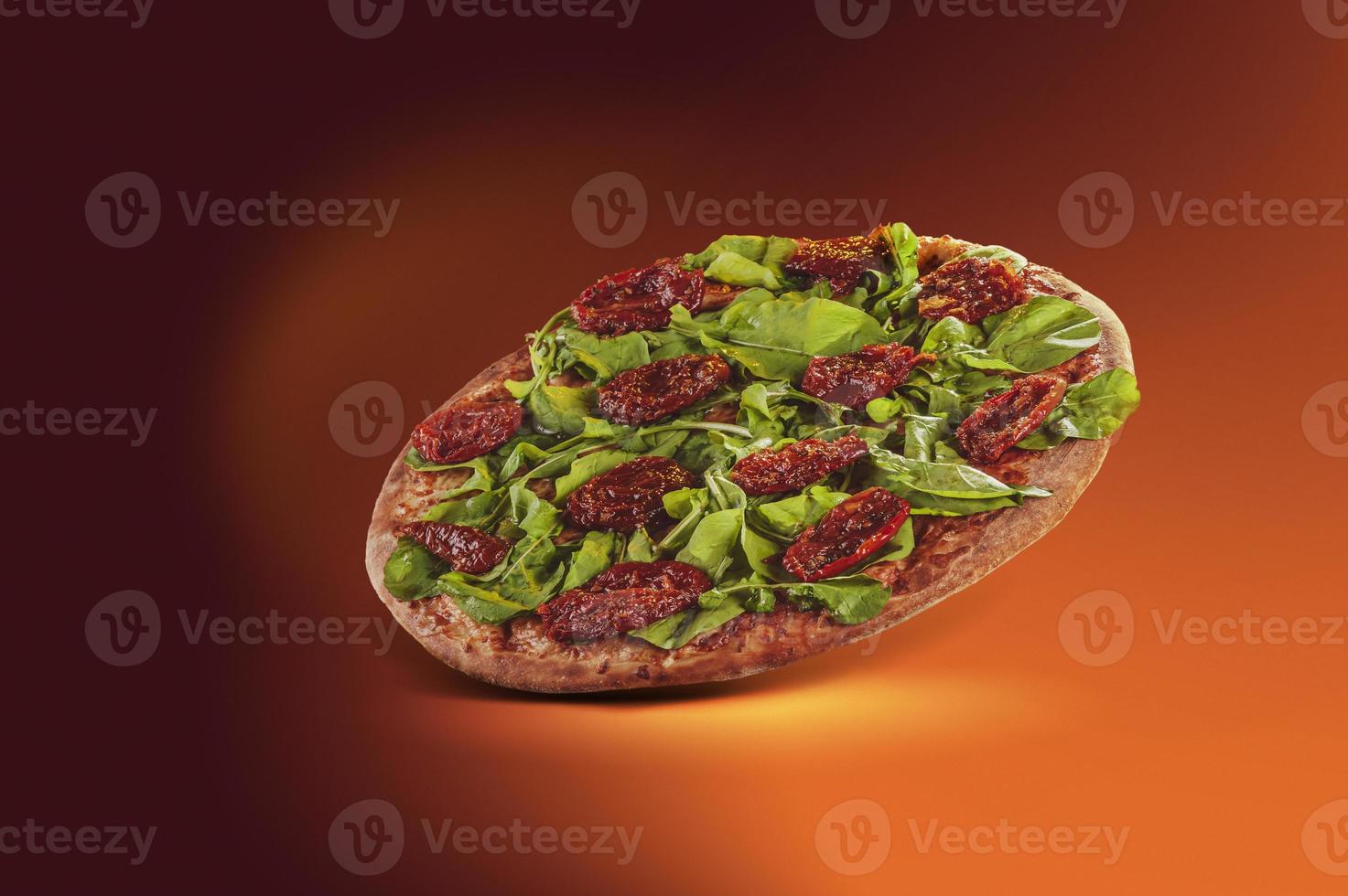 pizza brésilienne avec sauce tomate, mozzarella, roquette, tomates séchées et origan dans une boîte de livraison photo
