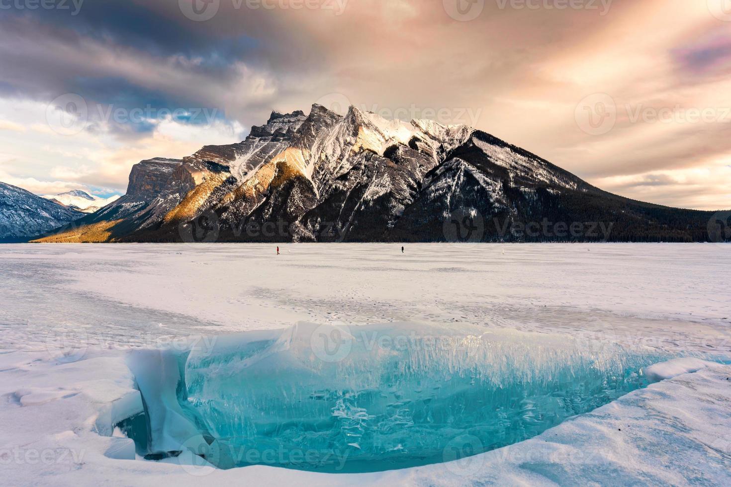 congelé Lac minnewanka avec rocheux montagnes et fissuré la glace de le Lac dans hiver à banff nationale parc photo