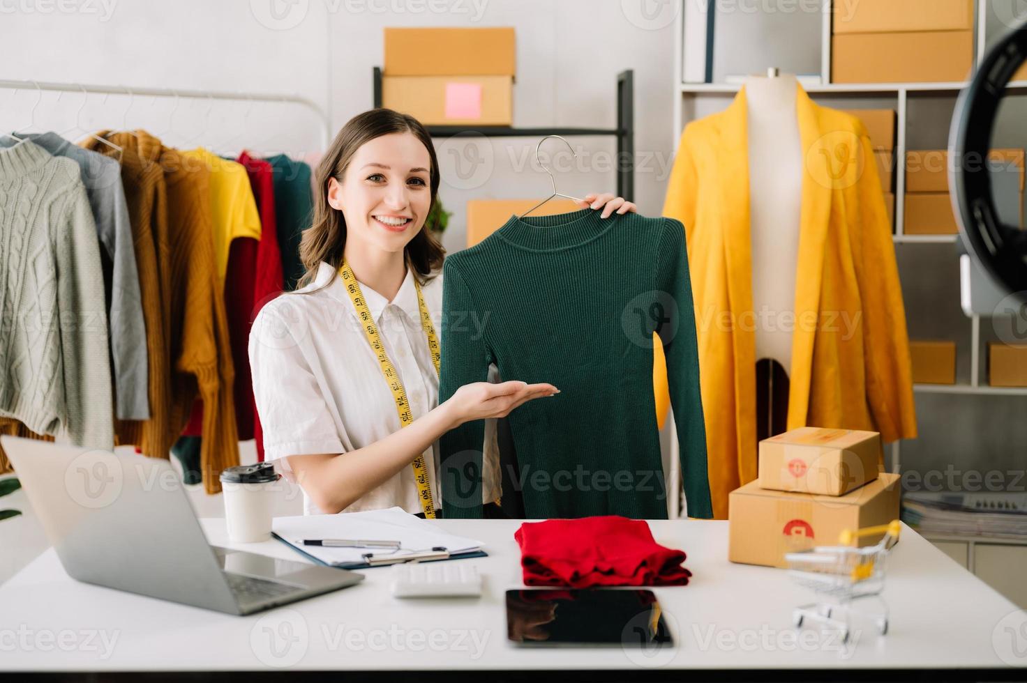 asiatique tailleur femme travail sur vêtements dans adaptation atelier. magnifique Jeune femelle mode designer sourire et après Succès dans studio photo