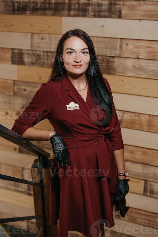 Une femme gérante de restaurant en gants jetables noirs posant dans un café photo