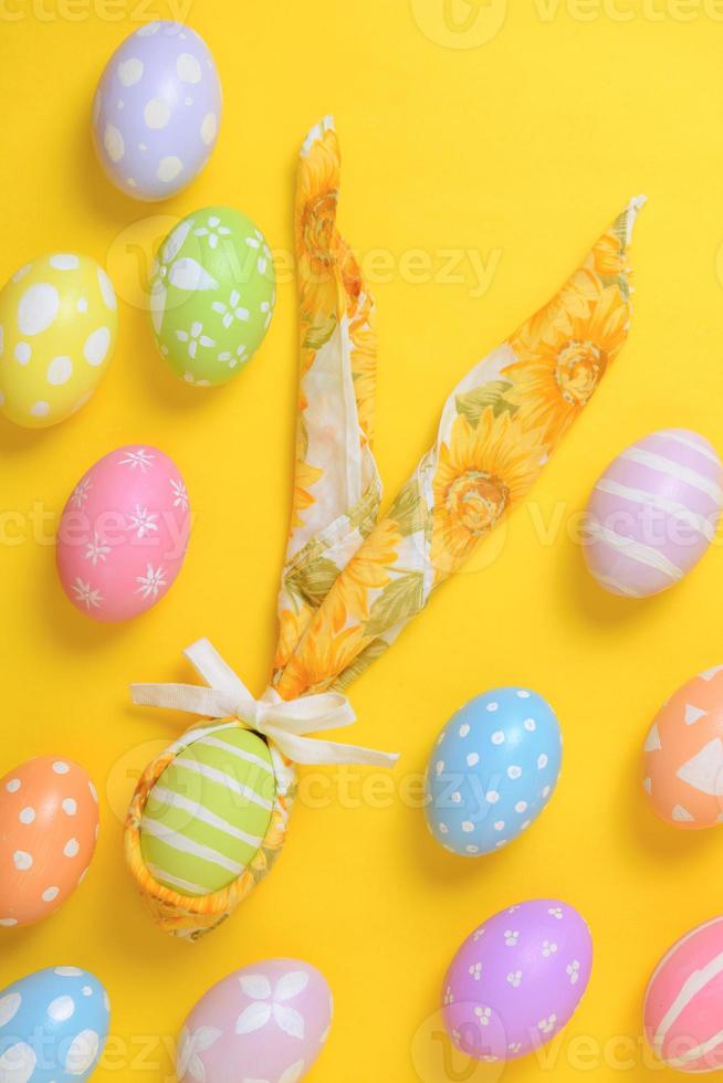 coloré peint Pâques Oeuf décoré avec une serviette de table dans le forme de une lapin sur une Jaune Contexte photo