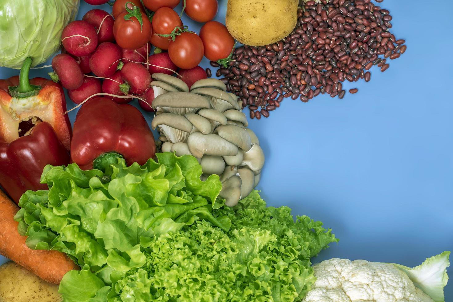 produits pour un régime végétarien de désintoxication de chou-fleur, laitue, radis, tomates, champignons, haricots et poivron rouge sur fond bleu photo