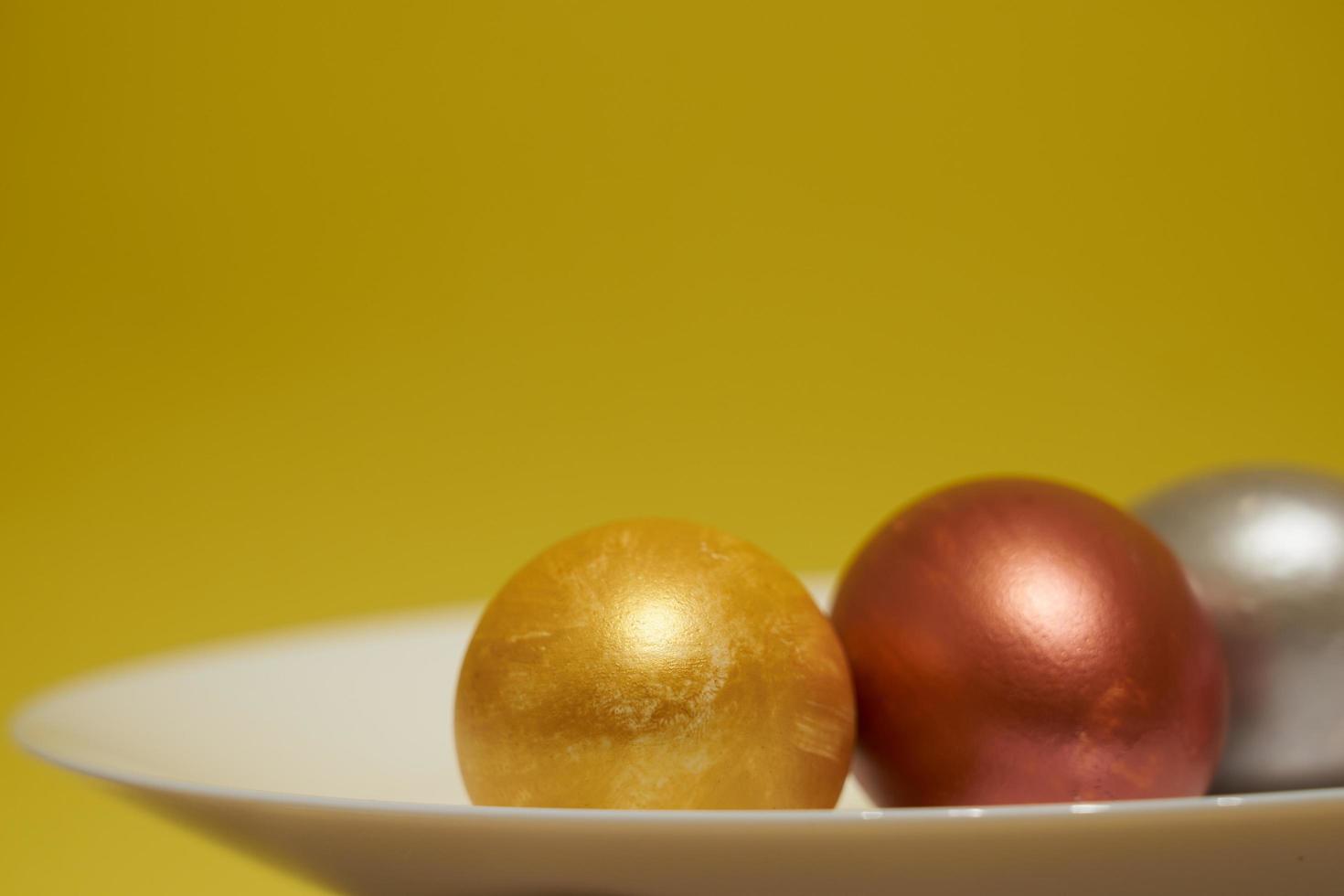 oeufs peints sur une plaque blanche avec un fond jaune pour Pâques photo