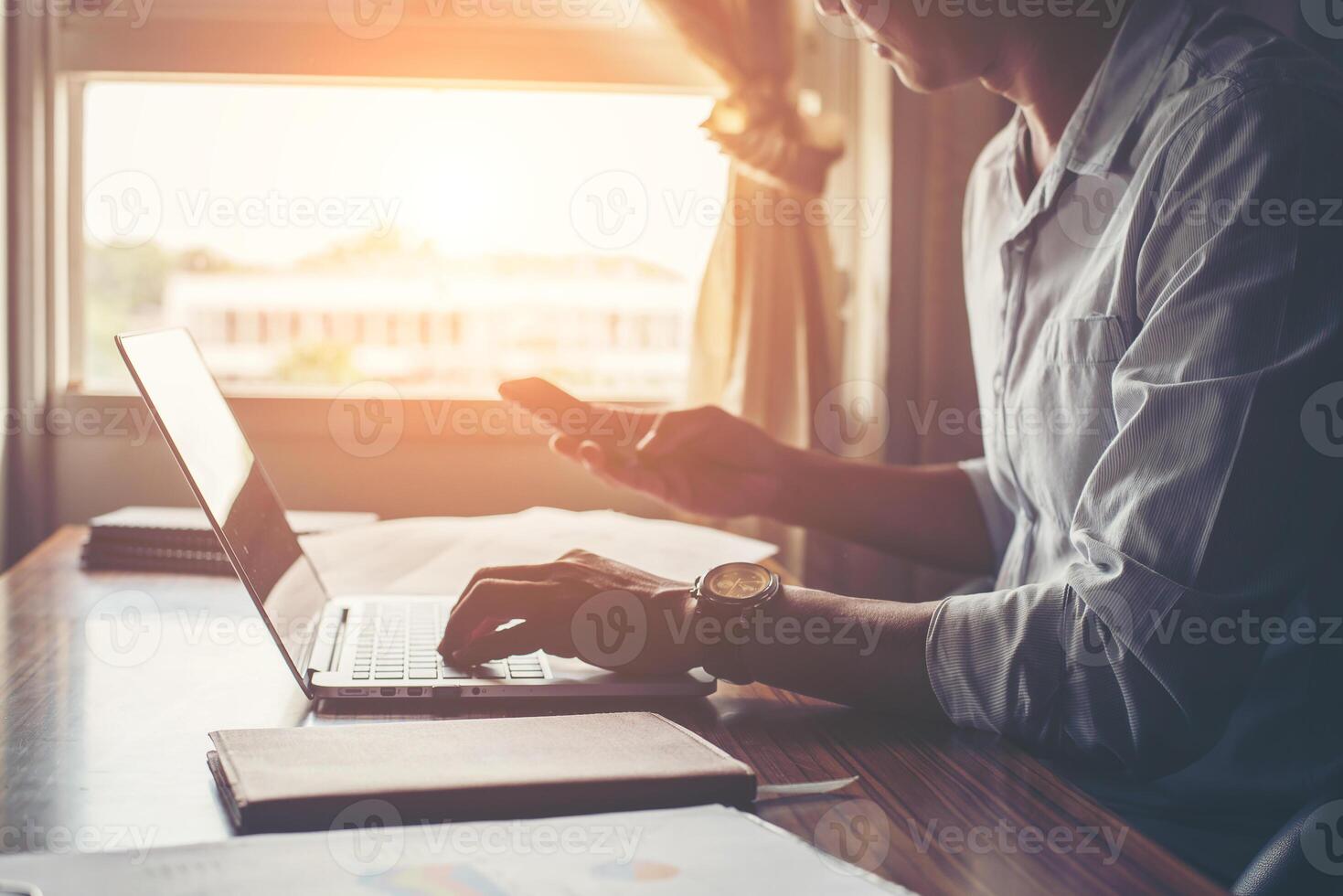 mains d'homme d'affaires utilisant un téléphone portable avec un ordinateur portable au bureau. photo