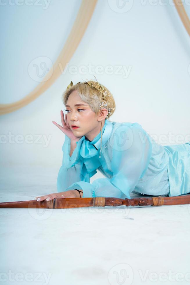 une Princesse dans une bleu robe posant sur le sol avec une arc photo