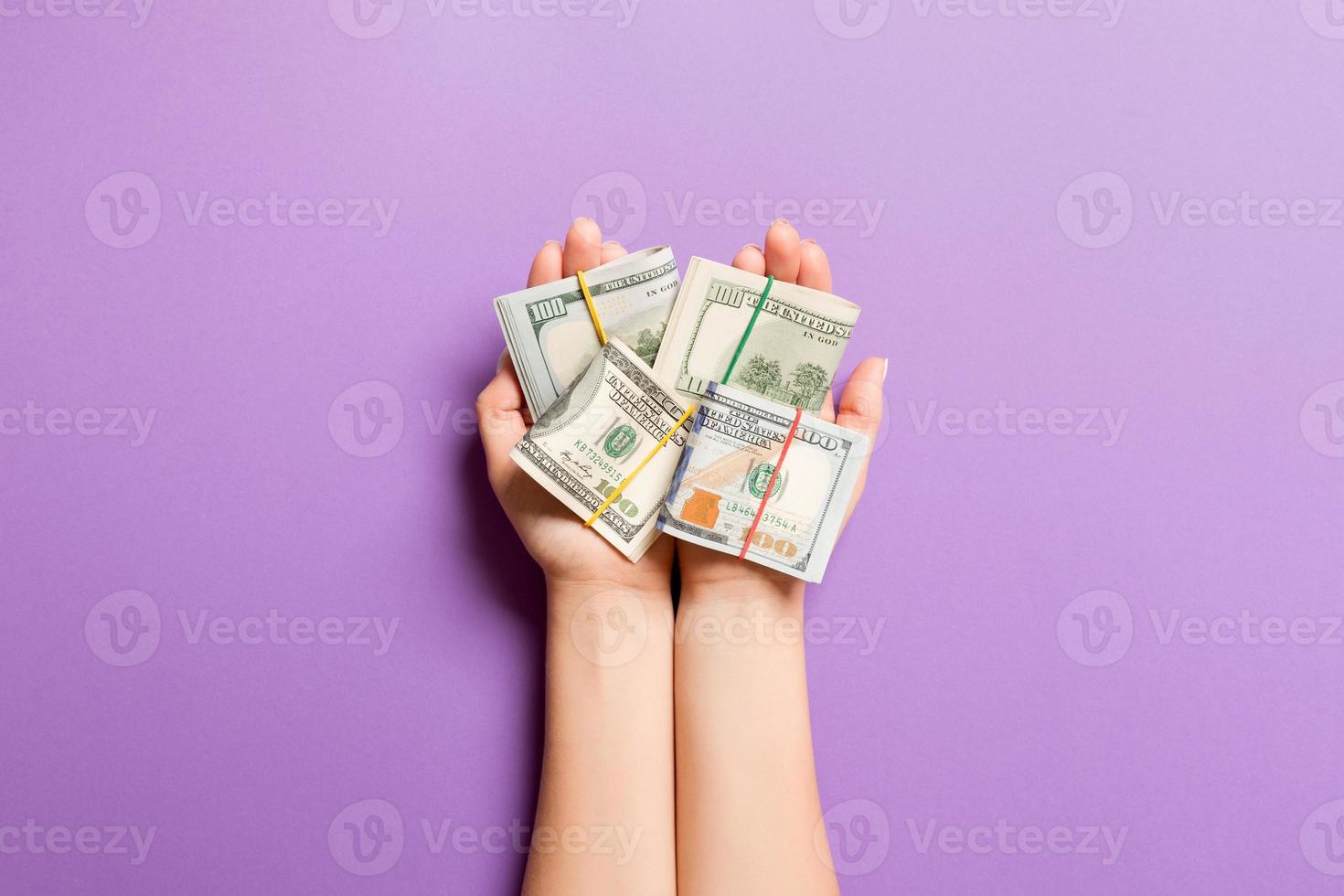 Haut vue de roulé en haut dans tubes dollar factures dans femelle paumes sur coloré Contexte. la pauvreté et dette concept photo