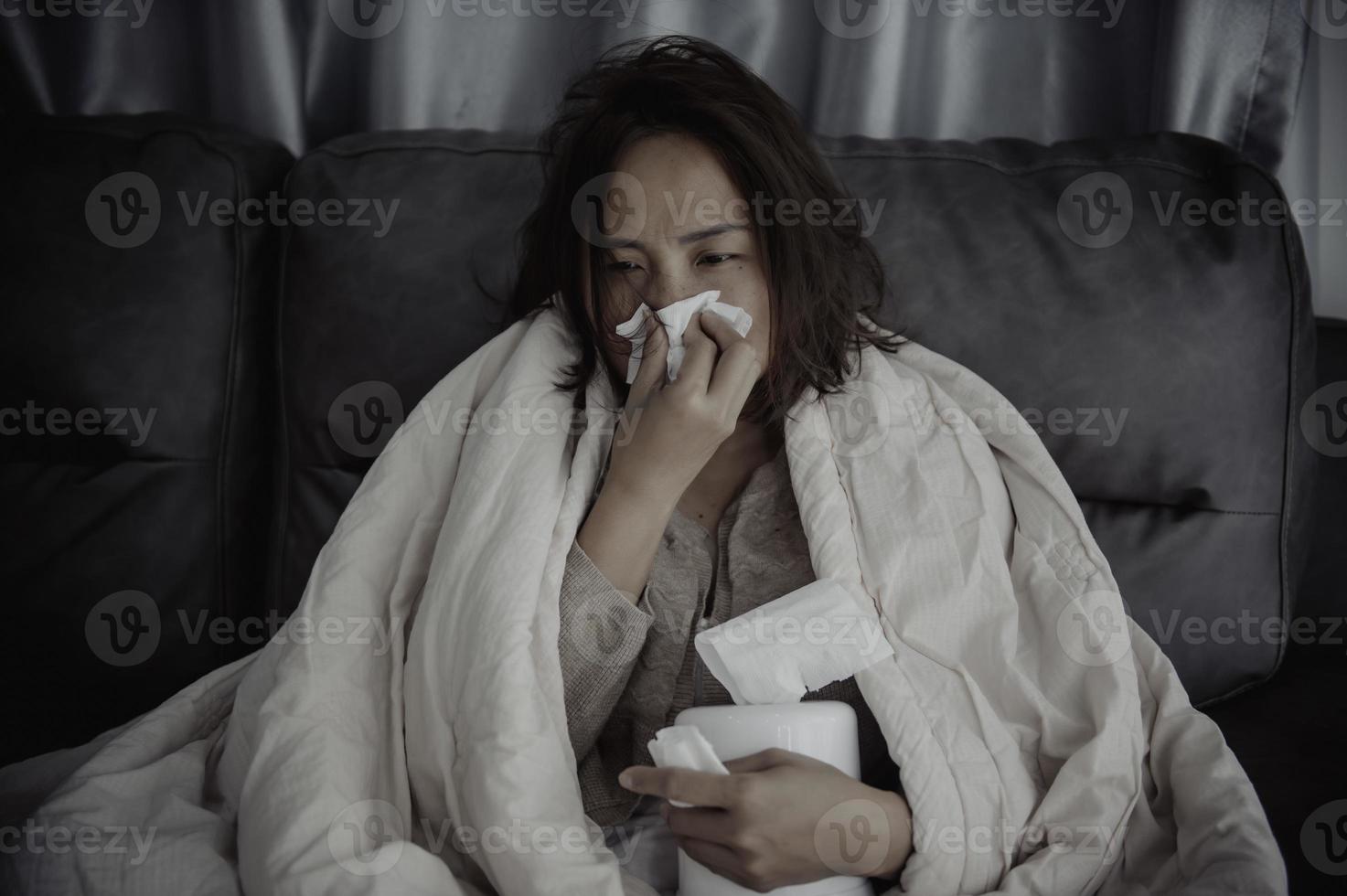 une femme malade asiatique s'assoit sur le canapé reste à la maison, la femme se sentait mal, voulait s'allonger et se reposer, forte fièvre photo