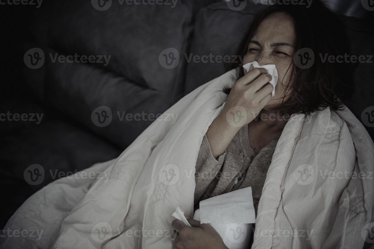 une femme malade asiatique s'assoit sur le canapé reste à la maison, la femme se sentait mal, voulait s'allonger et se reposer, forte fièvre photo