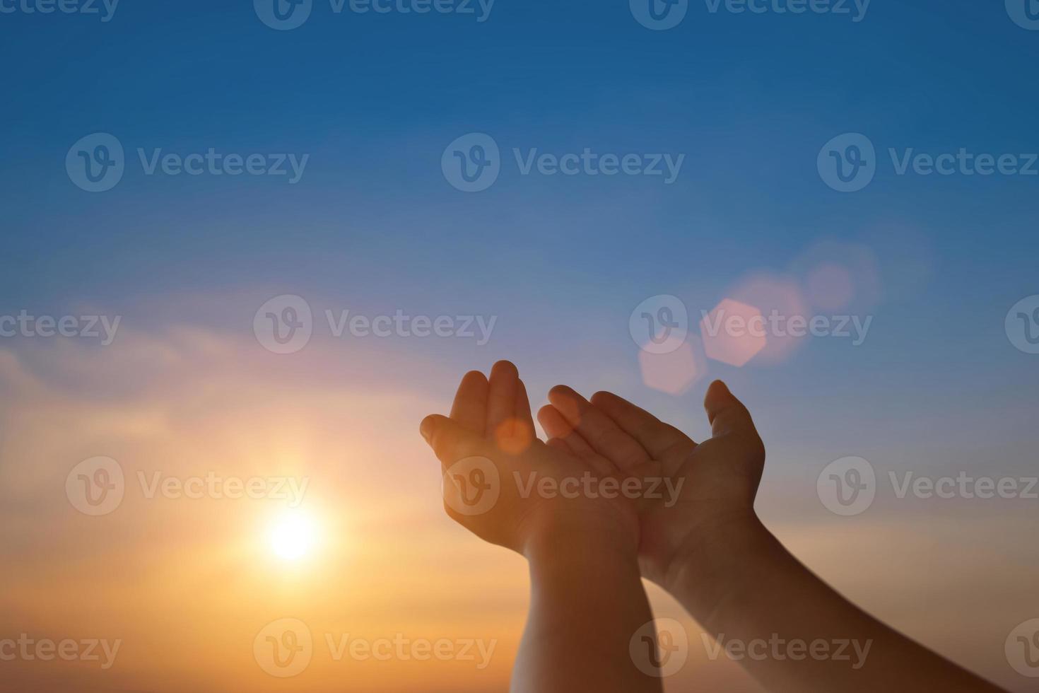 enfant ouvert vide mains avec paumes en haut pour espérer sur le coucher du soleil Contexte. liberté spiritualité concept. photo