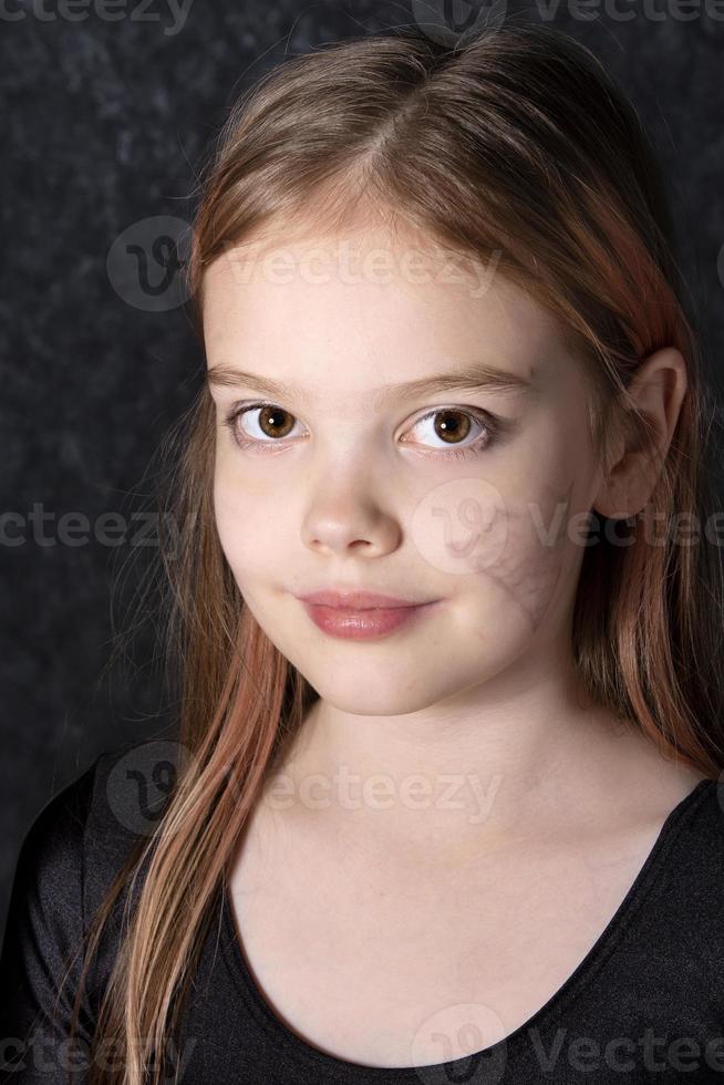 portrait de une peu fille avec une araignée la toile dessin sur sa affronter. photo