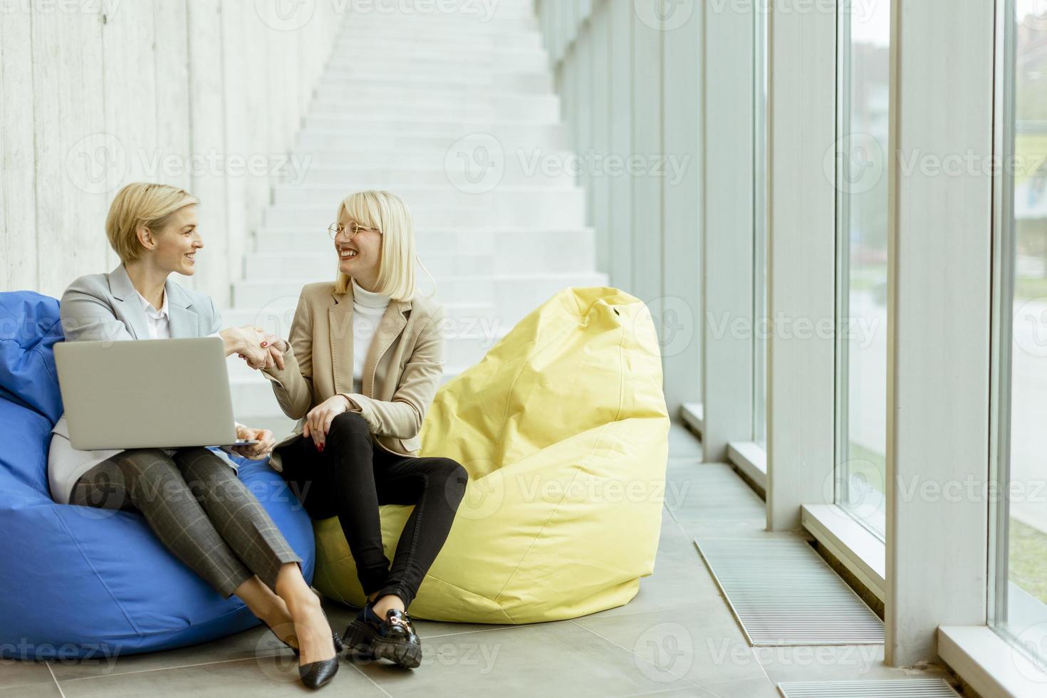 femmes d'affaires utilisant un ordinateur portable sur des sacs paresseux dans le bureau moderne photo