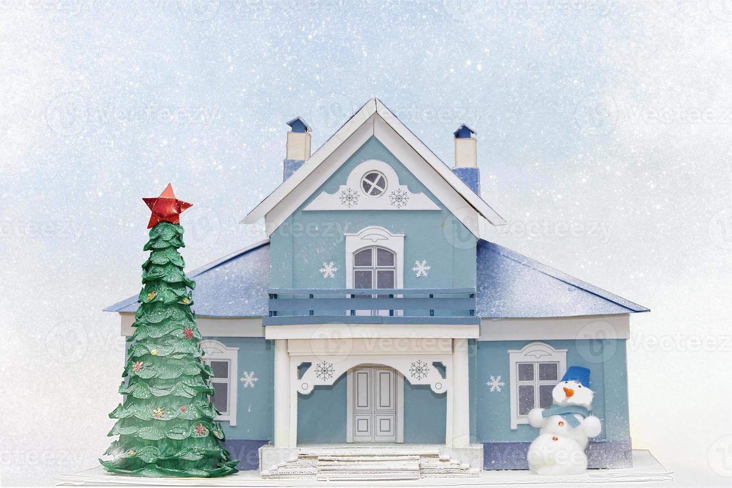 Noël carte. maison Noël arbre bonhomme de neige sur une bleu neigeux Contexte. photo