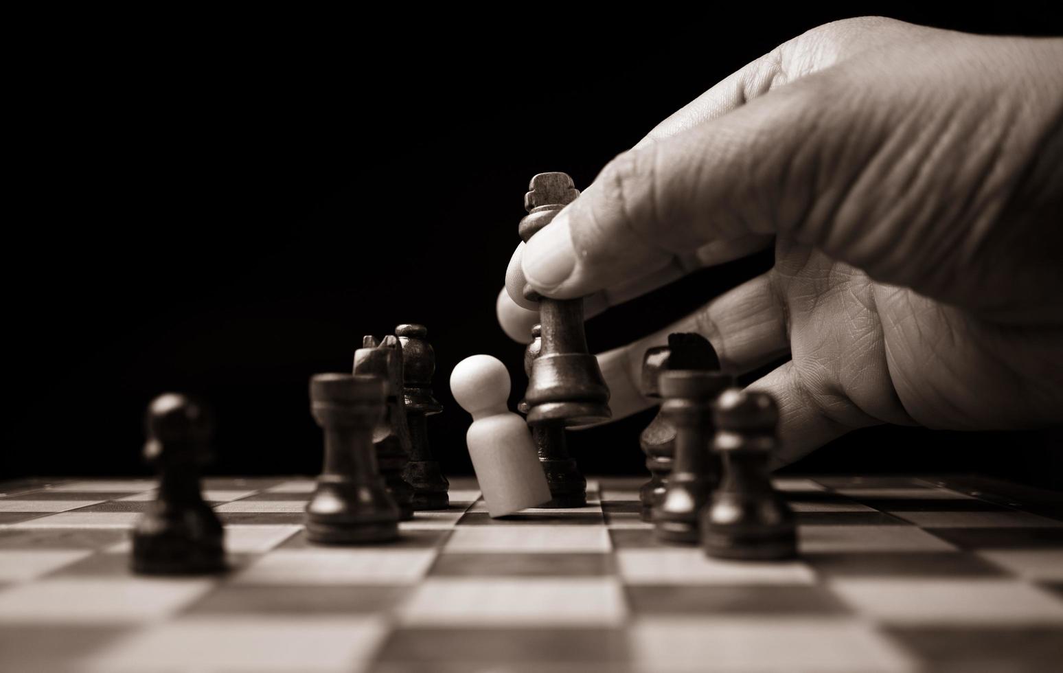 gros plan des mains homme d'affaires confiant déplaçant la figure d'échecs dans le jeu de succès de la compétition. le jeu d'échecs est l'analyse du développement, la stratégie et le plan, le concept de gestion ou de leadership. photo